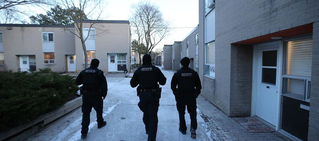 Three Toronto police officers walking in townhouse community