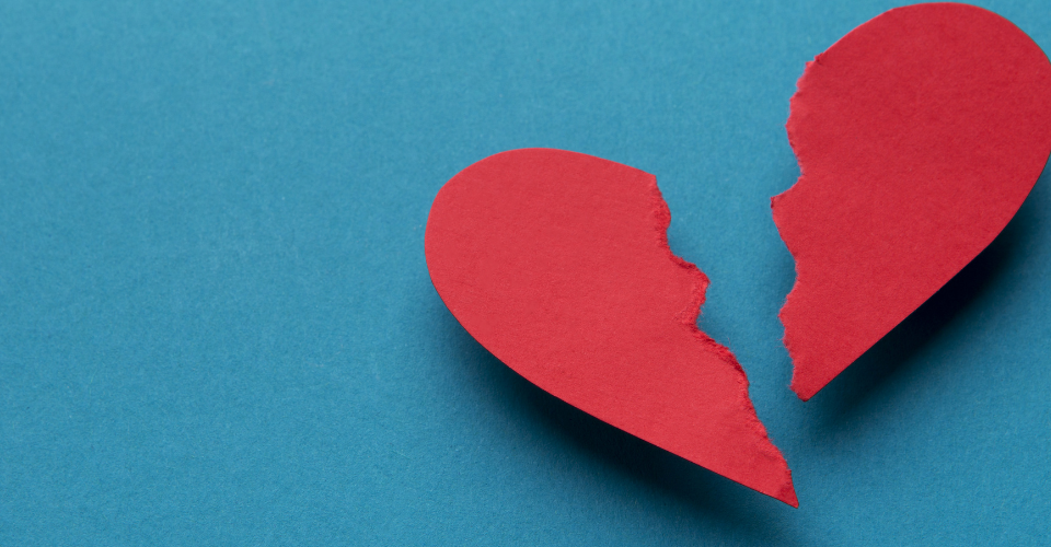 Red paper heard torn in half with a blue background