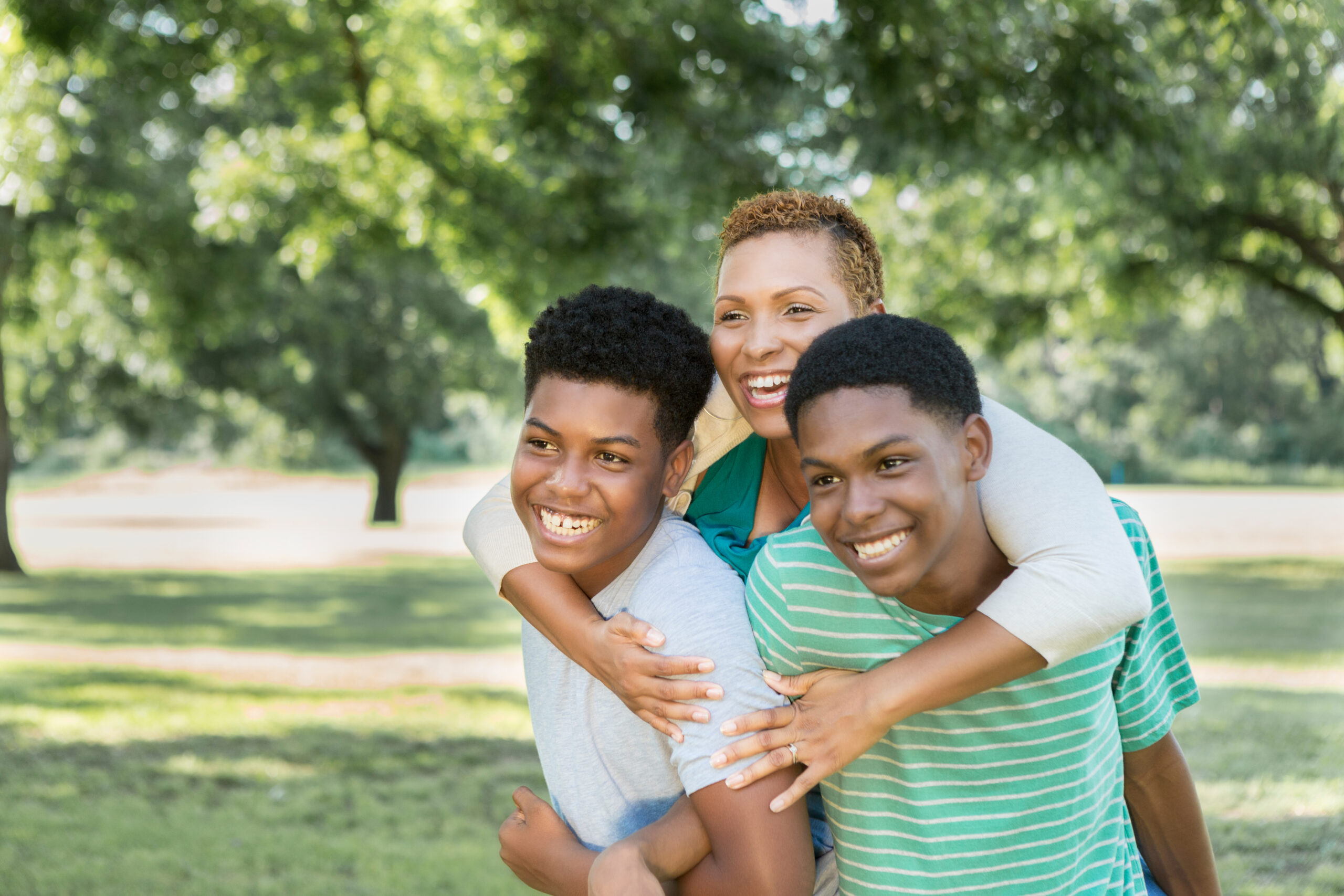 African American mom hugging her two teen sons