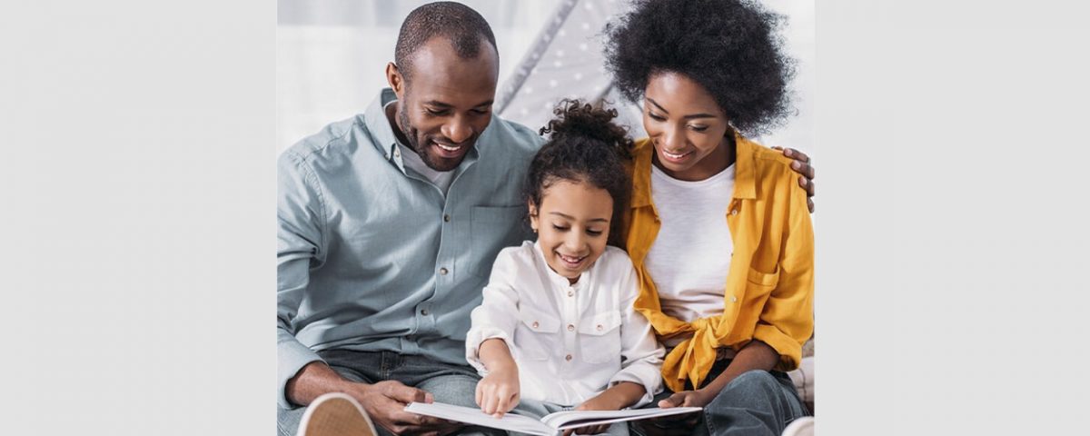 father and mother read book with little girl
