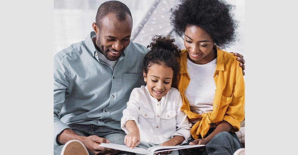 father and mother read book with little girl