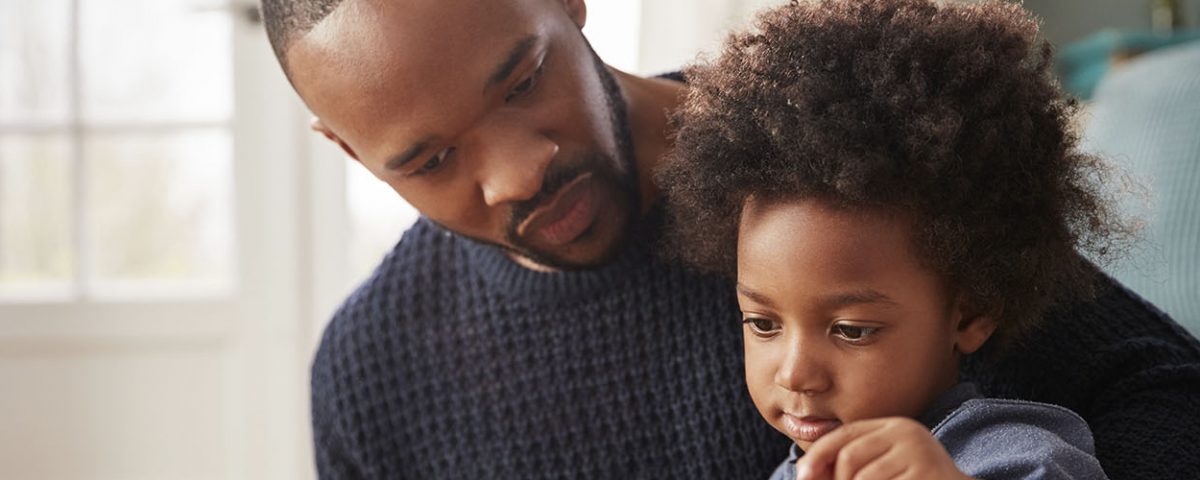 Father with child on his lap reading a book