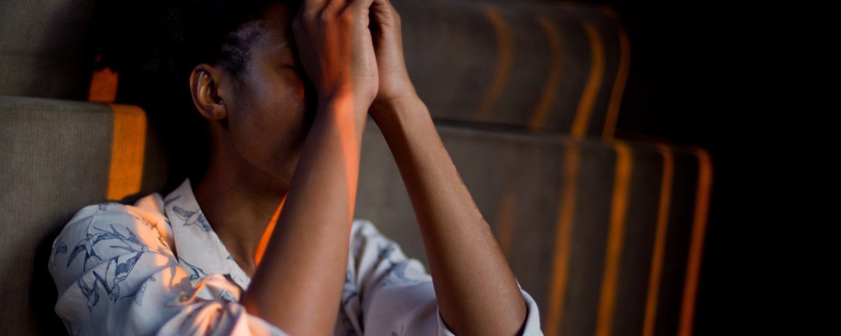woman sitting against wall stressed