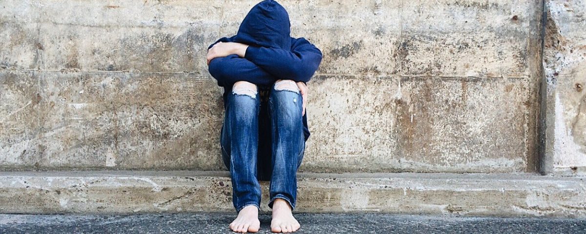 sad youth looking down into arms