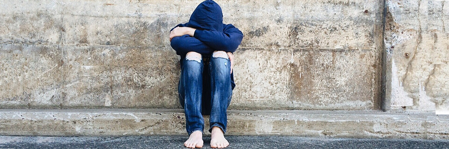 sad youth looking down into arms