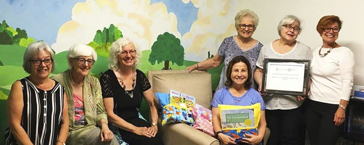 group of children sitting on a couch reading together