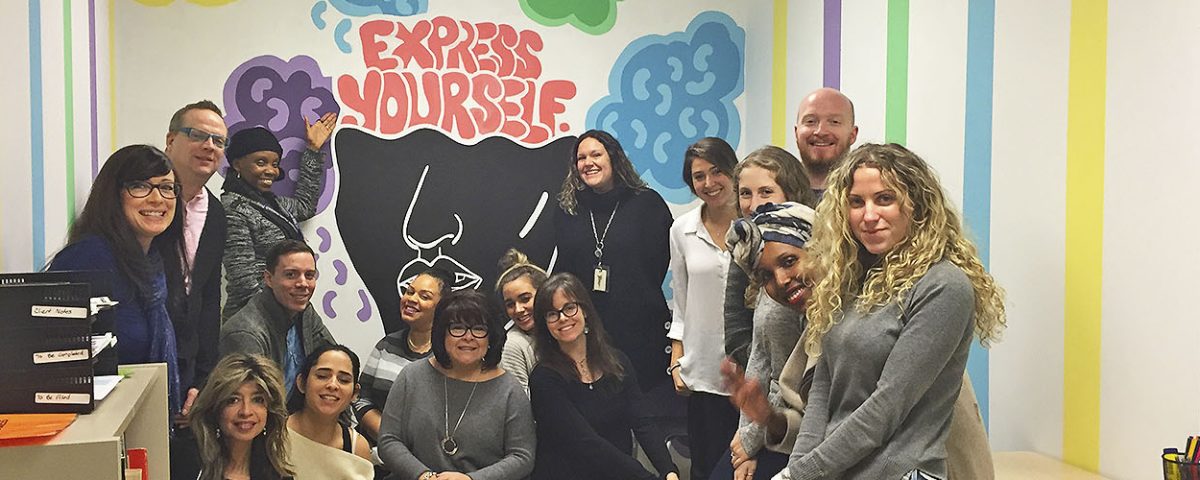 group of people huddled in front of youth hub mural