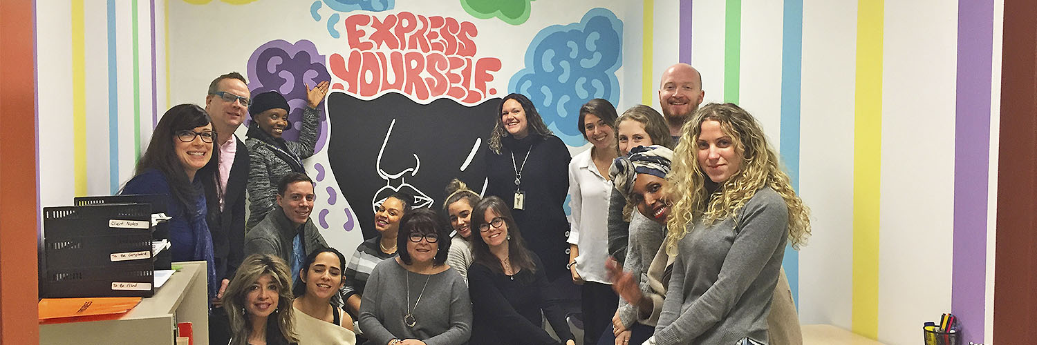 group of people huddled in front of youth hub mural